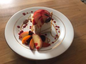 a piece of cake on a white plate with fruit at AYATO l’auberge de l’abbaye in Sorde-lʼAbbaye