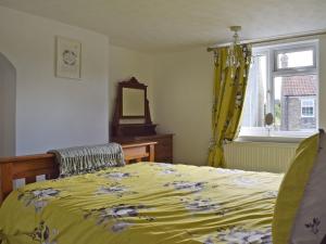 a bedroom with a bed with a yellow comforter and a window at Florence Cottage in Pakefield