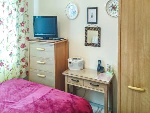 a bedroom with a bed and a desk with a television at Foxgloves Bungalow Uk39618 in Welcombe