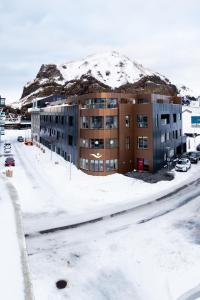 un edificio de apartamentos con una montaña cubierta de nieve en el fondo en Westman Islands Inn en Islas Vestman