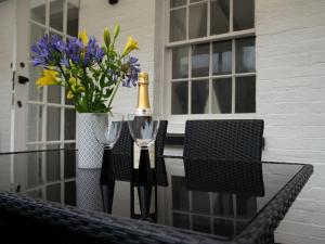 Pebble Cottage في Felpham: زجاجة من الشمبانيا وكأسين على طاولة مع الزهور