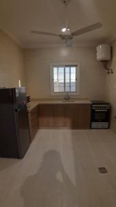 eine Küche mit einem schwarzen Kühlschrank und einem Fenster in der Unterkunft نايتس للوحدات المفروشة in Tabuk