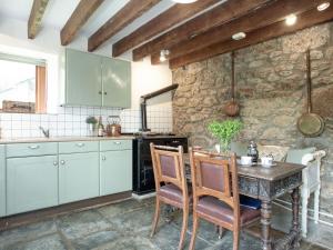 a kitchen with a table and a stone wall at Coach House - Uk32684 in Sheepstor