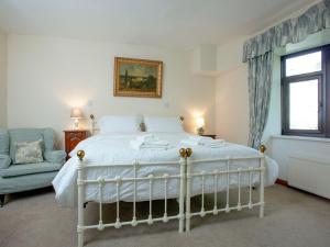 a bedroom with a white bed and a chair and a window at Coach House - Uk32684 in Sheepstor