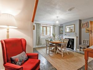 a living room with a table and a red chair at The Cottage in Wells
