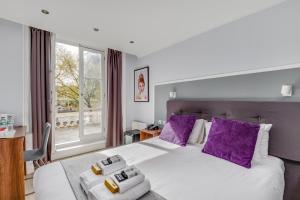 a bedroom with a large white bed with purple pillows at 1 Lexham Gardens Hotel in London +121 photos