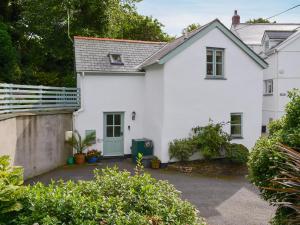 a white house with a gate and a driveway at Thimble Cottage in Hartland