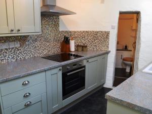 a kitchen with white cabinets and a sink at Scot Beck Cottage in Troutbeck