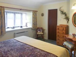 a bedroom with a bed and a dresser and a window at Waterwheel in Dalbeattie