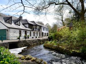 un río frente a las casas y un puente en Waterwheel en Dalbeattie