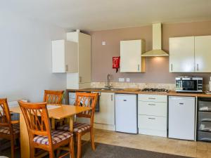 uma cozinha com armários brancos e uma mesa e cadeiras de madeira em Dovecote Annex em Mablethorpe