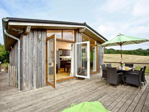 une petite maison en bois avec une table et un parasol dans l'établissement Garfield Lodge, à Hawkchurch