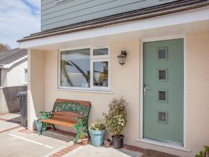 a green door on a house with a bench at Driftwood Cottage in Galmpton-on-the-Dart