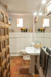 a bathroom with a sink and a toilet and a mirror at Cuencaloft Casa S-XVII "La Catedral" in Cuenca