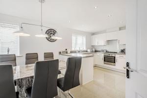 a white kitchen with a dining table and chairs at Roma in North Walsham