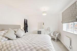 a white bedroom with a large bed and a chair at Roma in North Walsham