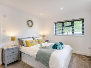 a white bedroom with a bed and a window at Willow Cottage in Stonham Aspall
