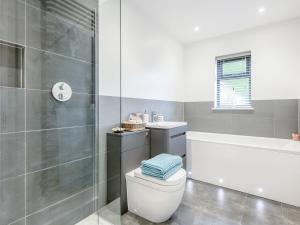a bathroom with a shower and a toilet and a tub at Willow Cottage in Stonham Aspall