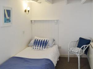 a small bedroom with a bed and a chair at Beach Corner Cottage in Gorran Haven