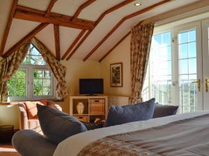 a bedroom with a bed and a tv and windows at Meadow Croft in Llangeinor