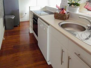 a white kitchen with a sink and a dishwasher at Robins Nest in Broomhill