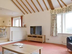 a living room with a tv and a table at Leyfield Coach House in Kirkby Lonsdale