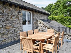 a wooden table and chairs in front of a stone house at Leyfield Coach House in Kirkby Lonsdale
