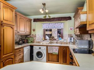 a kitchen with wooden cabinets and a washer and dryer at Oak Cottage in Beckermonds