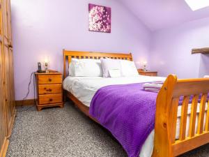 a bedroom with a wooden bed with a purple blanket at Oak Cottage in Beckermonds