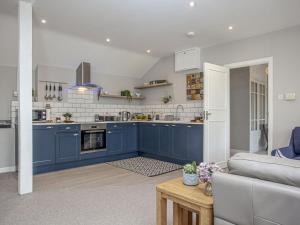 a kitchen with blue cabinets and a living room at Old Seaway Mews in Stokeinteignhead