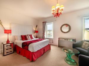 a bedroom with a bed and a chair and a chandelier at Babbacombe House in Torquay