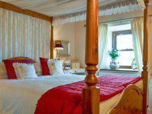 una camera con letto a baldacchino e coperta rossa di Rosedale- Lyl a Ireby