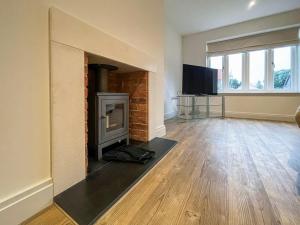 an empty living room with a fireplace and a television at Lavender Cottage in Stelling