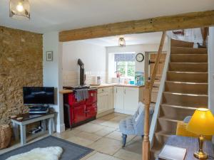 a kitchen with a staircase and a living room with a kitchen at Squirrel Cottage in Hook Norton