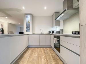 a kitchen with white cabinets and a wooden floor at Lavender Cottage in Stelling