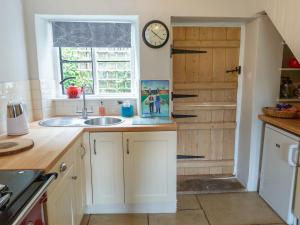 a kitchen with a sink and a clock on the wall at Squirrel Cottage in Hook Norton
