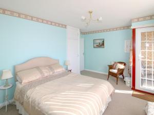 een slaapkamer met een bed met blauwe muren en een raam bij Kingsway Court in Seaford