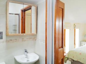 a bathroom with a sink and a mirror and a bed at The Garden Apartment - 28342 in Neatishead