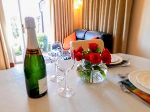 una mesa con una botella de vino y un jarrón de rosas rojas en The Garden Apartment - 28342, en Neatishead