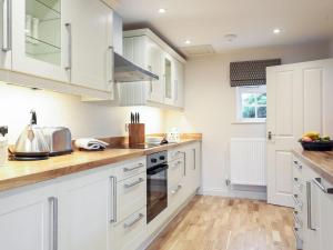 a kitchen with white cabinets and wooden floors at Garden Cottage in Settrington