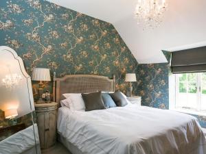 a bedroom with a white bed with floral wallpaper at Garden Cottage in Settrington