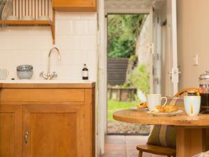 a kitchen with a sink and a table with food on it at Gamekeepers Cottage in Staple