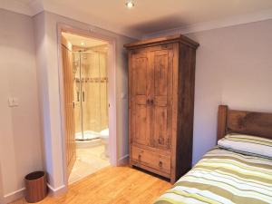 a bedroom with a wooden cabinet next to a bed at Bryn Menai - Hw7573 in Llanddeiniolen