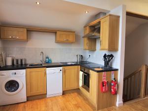 a kitchen with wooden cabinets and a washer and dryer at Bryn Menai - Hw7573 in Llanddeiniolen