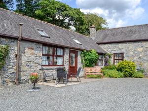 a stone cottage with a patio and chairs in front of it at Low Cordorcan - Uk5891 in Bargrennan