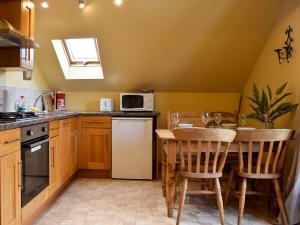 a kitchen with a table with chairs and a microwave at Mange-tout Maison - Uk32607 in Manton