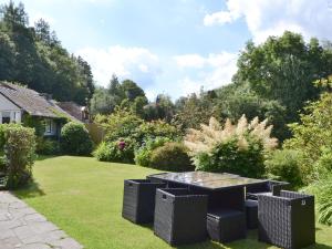 a garden with a table and chairs in the grass at Corner Cottage - Lp2 in Windermere