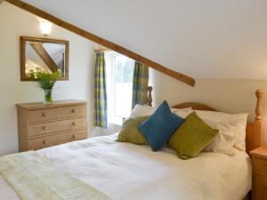 a bedroom with a white bed with blue and green pillows at Portington Lodge in Eastrington