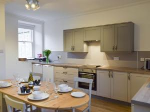 a kitchen with a wooden table with chairs and a dining room at Coachmans Cottage in Falkland
