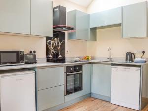 a kitchen with white cabinets and stainless steel appliances at The Pump House in Cawston